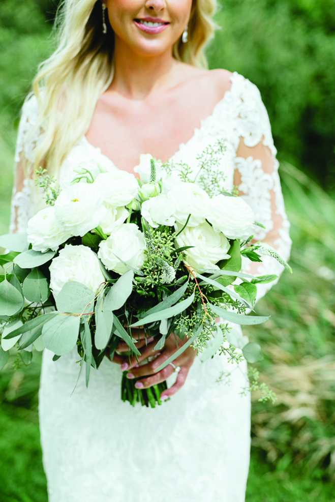 Chelsey holds her white wedding bouquet at Round Lake Vineyards & Winery