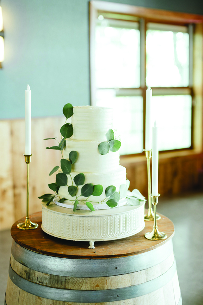 Chelsey and Tom's white, three-tiered wedding cake at their venue, Round Lake Vineyards & Winery