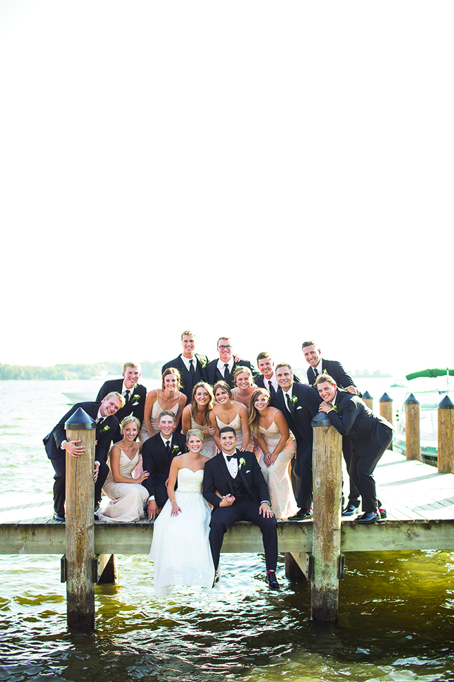 Paige, Jake and their wedding party sit on a dock at the Wayzata Country Club