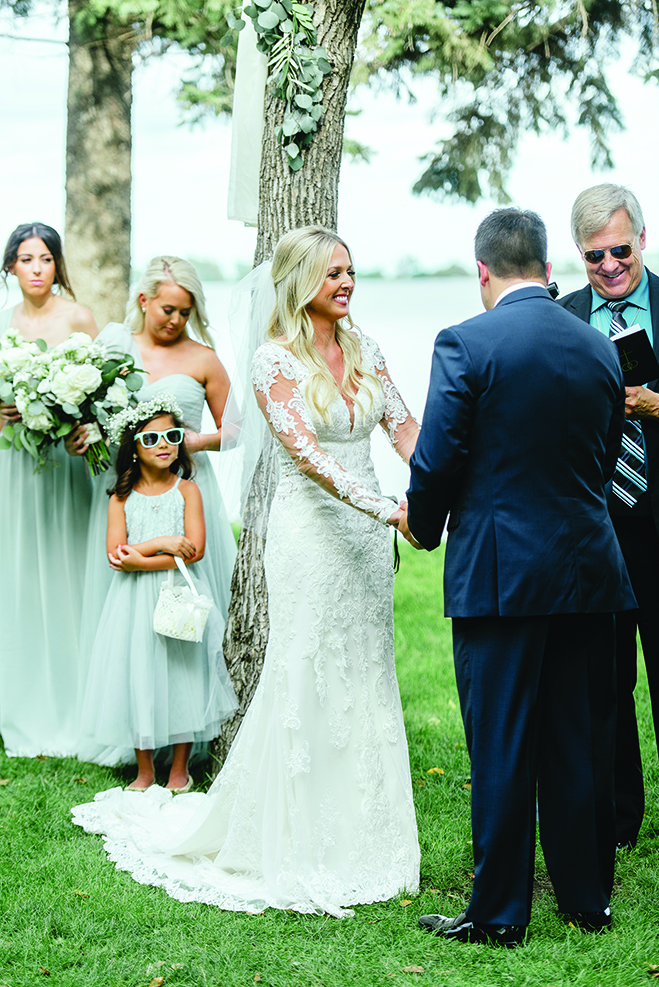Chelsey and Tom hold hands during their wedding ceremony at Round Lake Vineyards & Winery