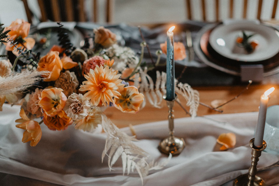 Orange blooms bedeck a table with blue tapers and flowing linen