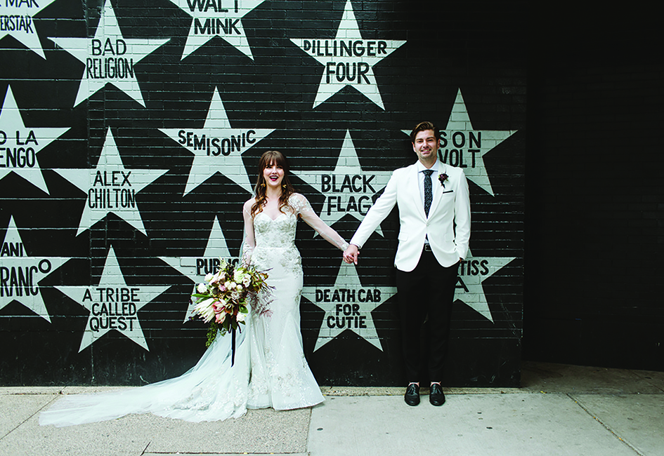 Sarah and Scott pose for a wedding photo in front of First Avenue.