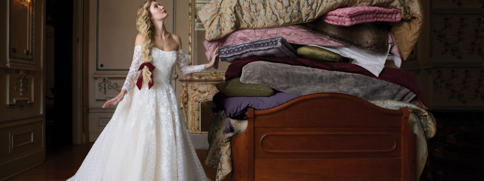 In "Princess and the Pea" style, the bride, in a lacy off-the-shoulder gown, contemplates a bed piled high with mattresses.