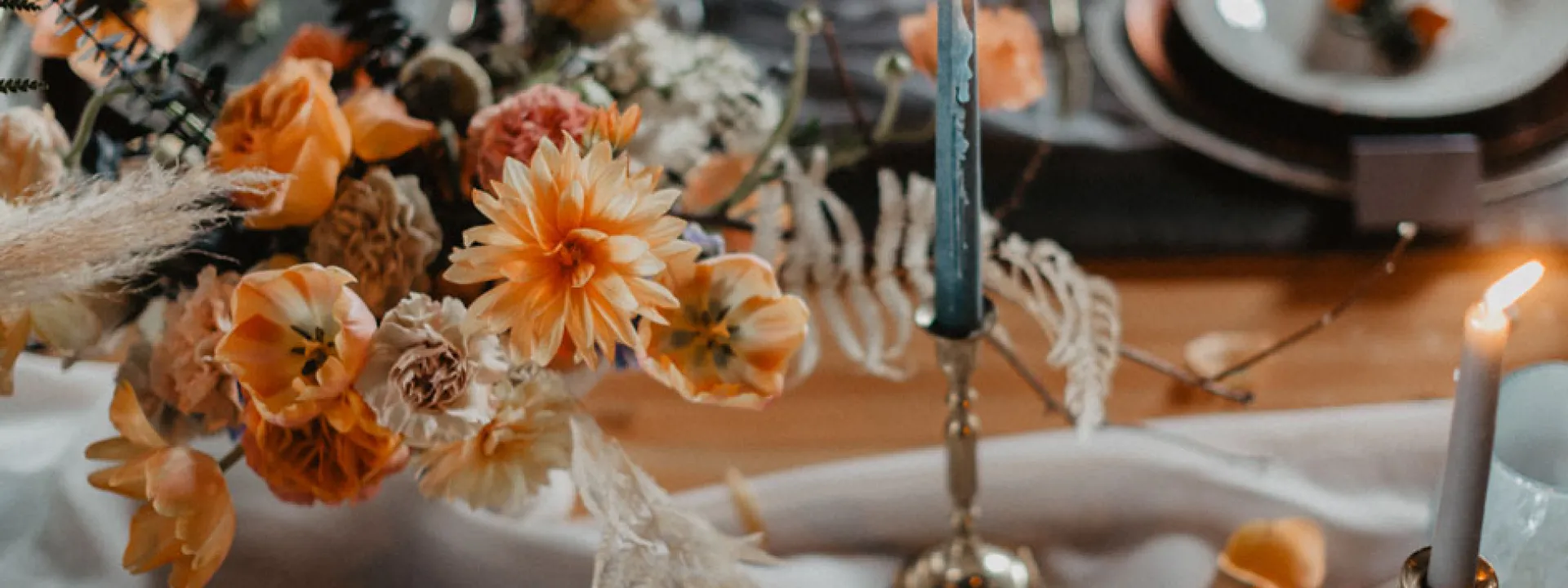Orange blooms bedeck a table with blue tapers and flowing linen