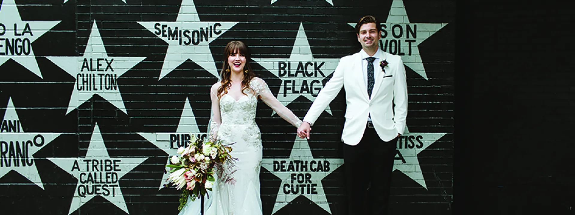 Sarah and Scott pose for a wedding photo in front of First Avenue.