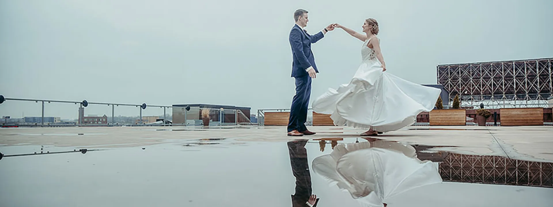 Bride and groom dance over a reflective puddle on the rooftop of A'BULAE.