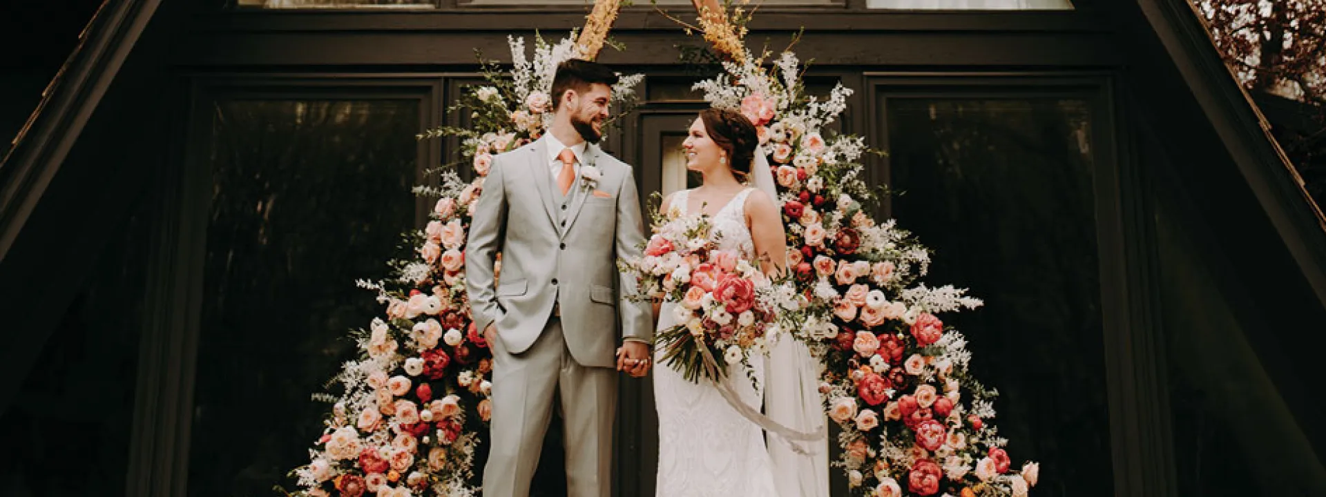 A lush floral arch serves as a ceremony backdrop at Grey Cloud House.